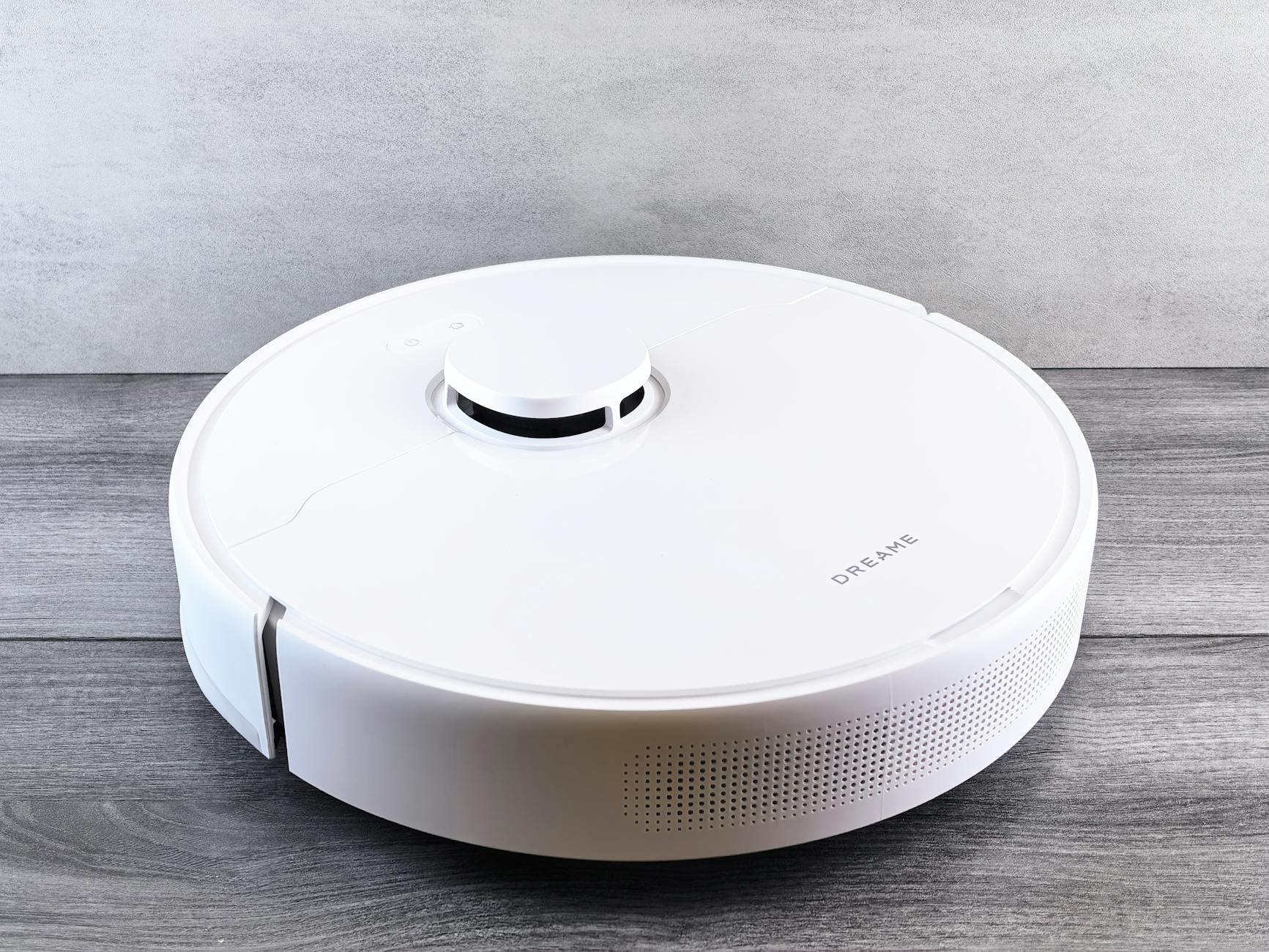 Biały robot odkurzający na drewnianej podłodze w nowoczesnym domu