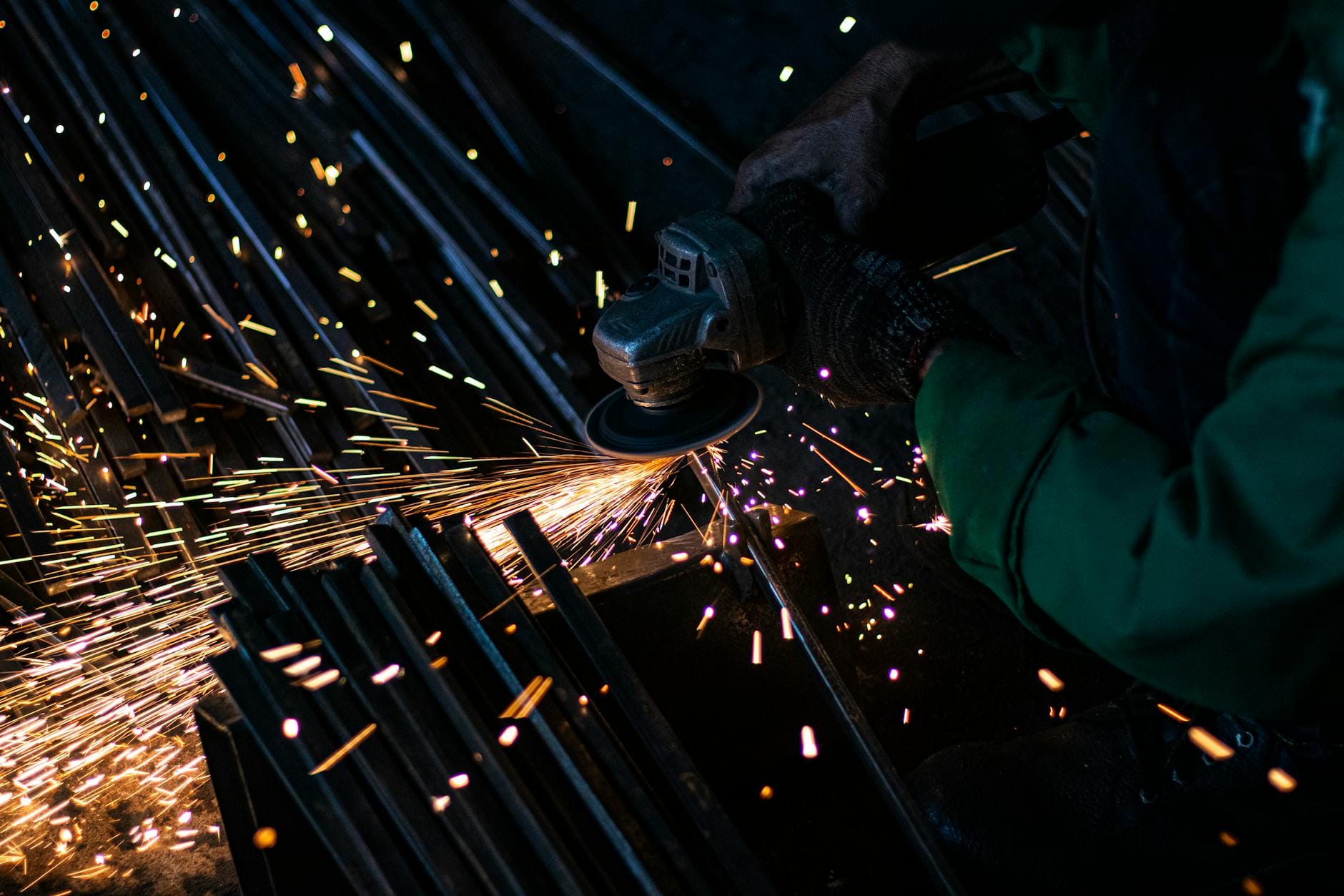 Pracownik szlifuje metal szlifierką kątową, lecą jasne iskry