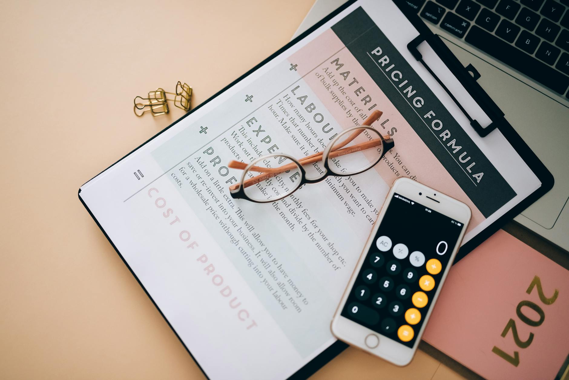 Kalkulator w telefonie, wzór na cenę i okulary na biurku