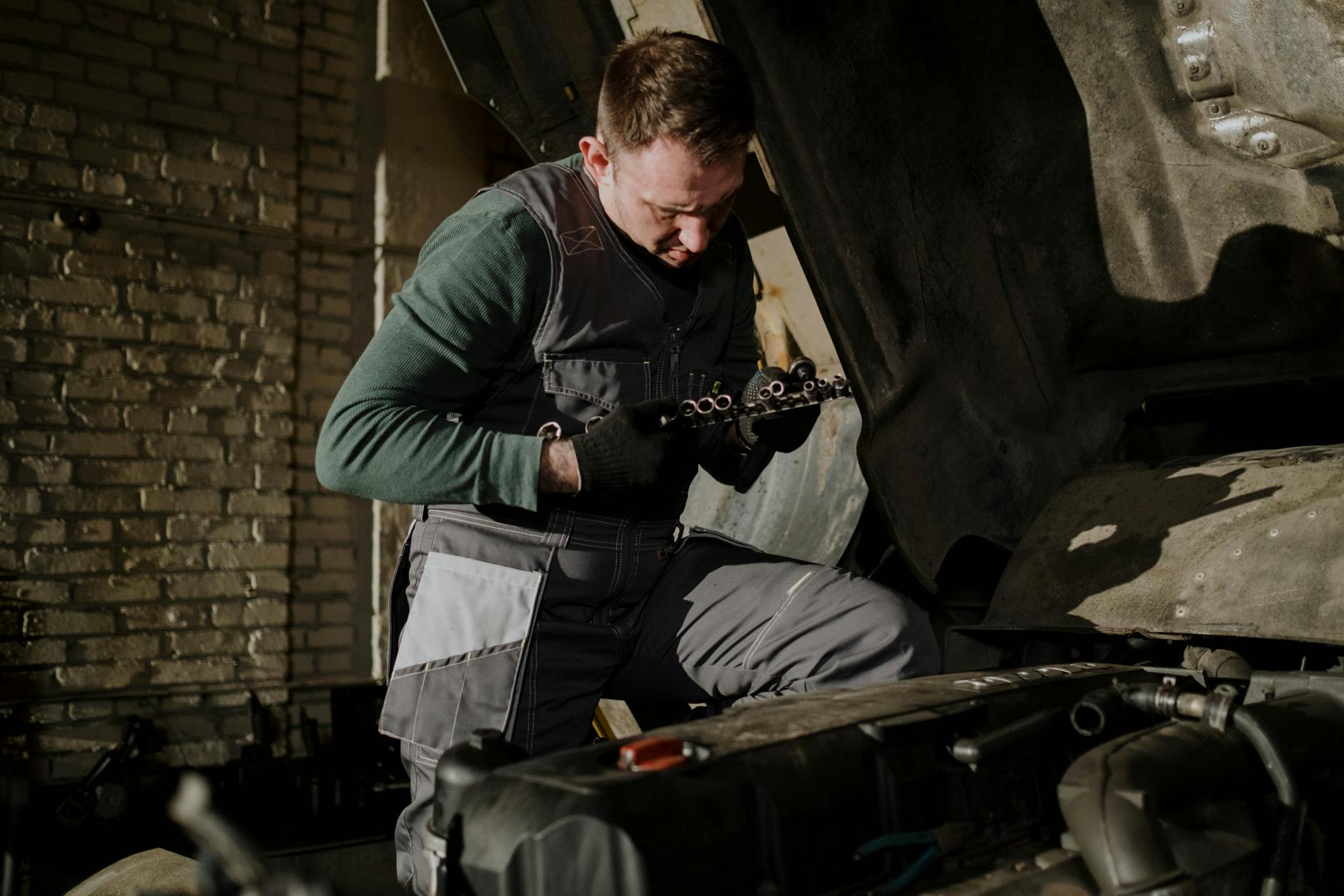 Mechanik w kombinezonie sprawdza elementy silnika w warsztacie