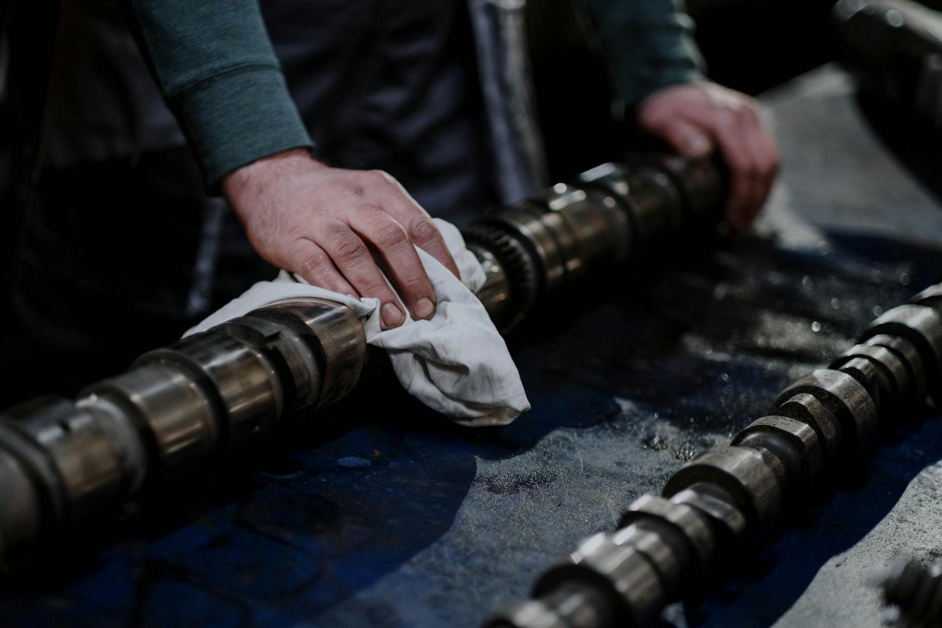 Mechanik w warsztacie czyści wałek rozrządu szmatką