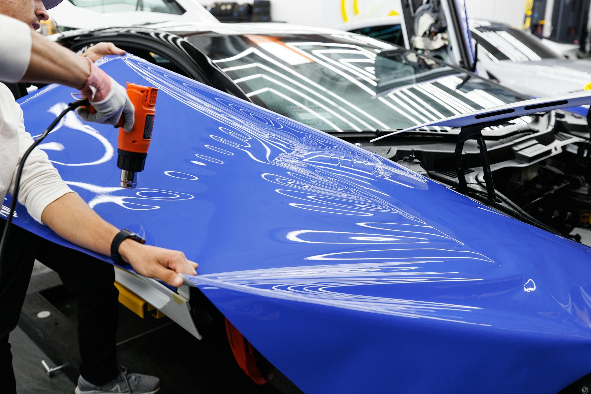 Technik używa opalarki do nakładania niebieskiej folii na auto