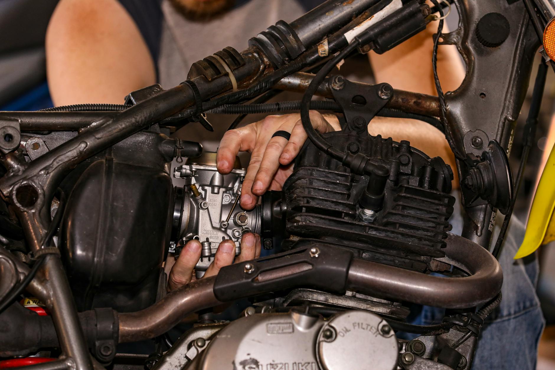 Mechanik naprawia silnik spalinowy, zbliżenie na dłonie przy pracy