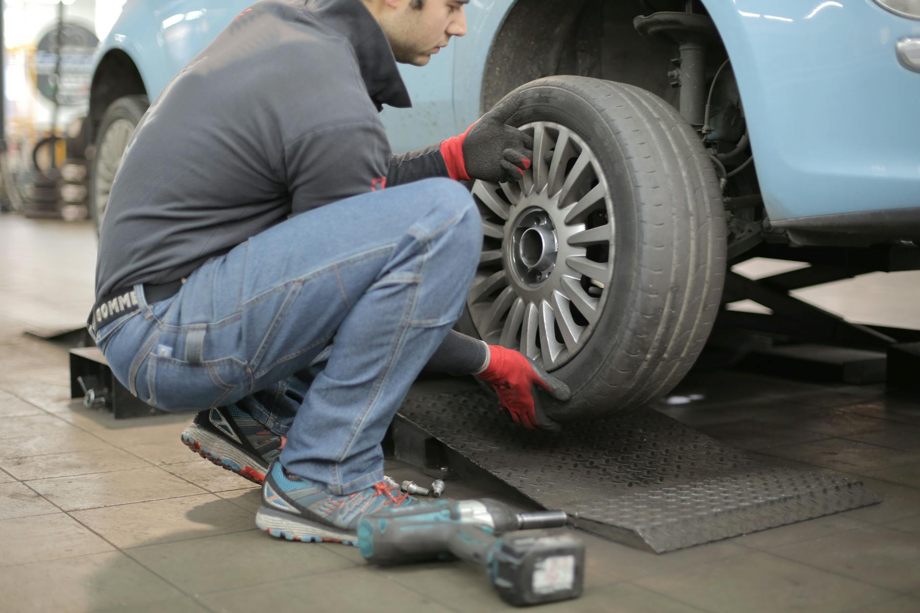 Mechanik w garażu wymienia koło auta, używając narzędzi