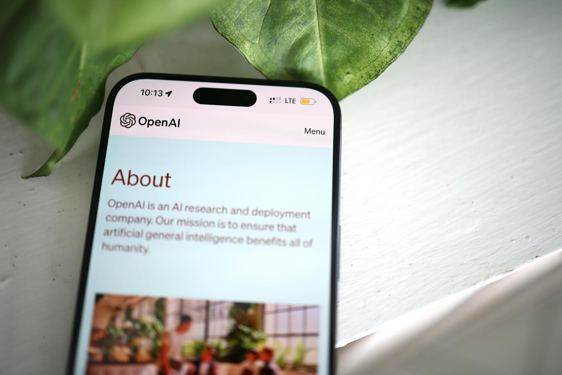 Zbliżenie smartfona z otwartą stroną OpenAI na tle zieleni