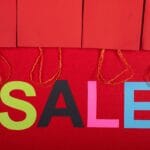 Outlet, ekspozycja, powystawowe: co oznaczają i jak negocjować cenę Kolorowy napis sale i czerwone torby zakupowe w sklepie