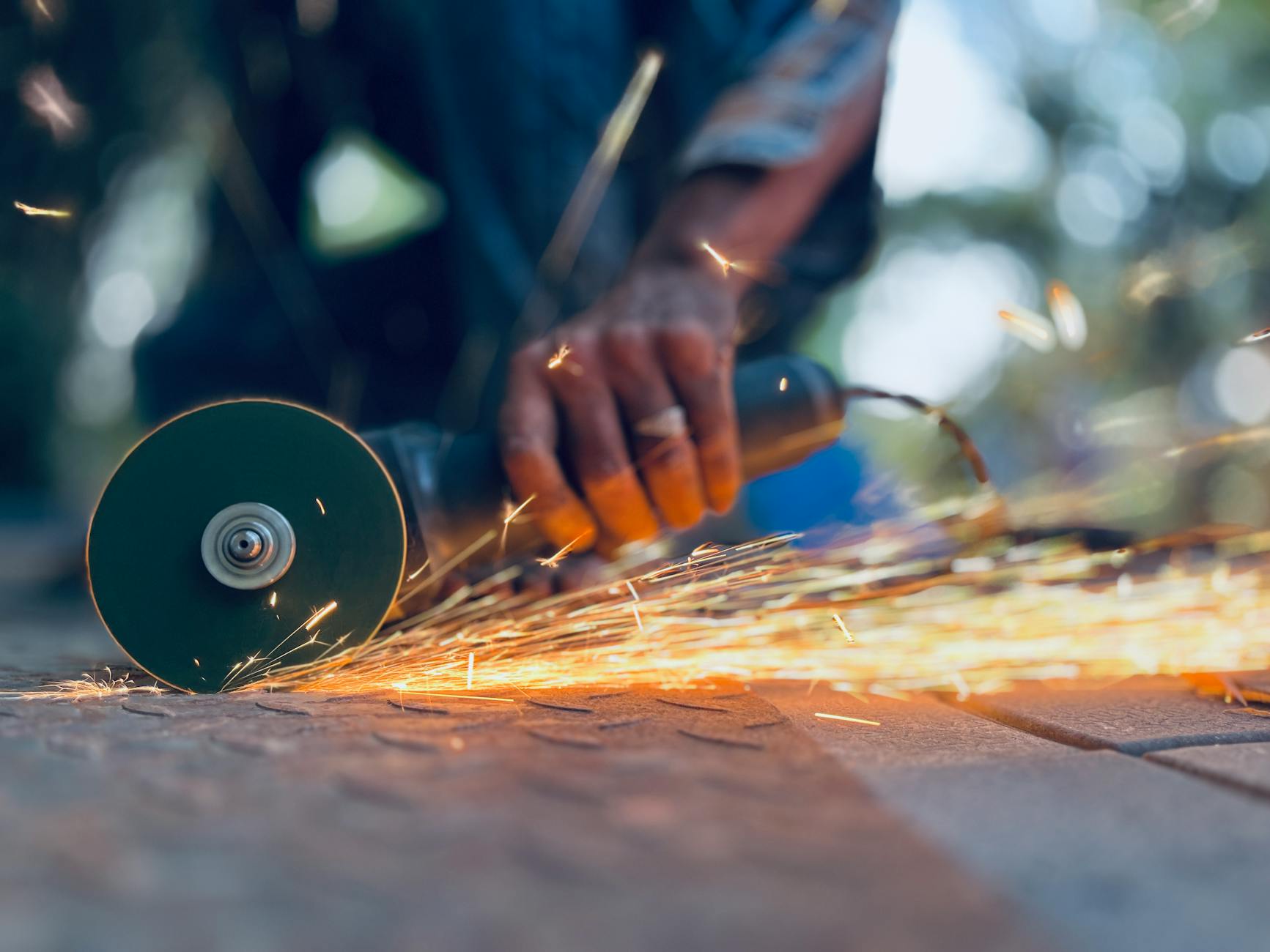 Pracownik szlifuje metal szlifierką kątową, lecą jasne iskry