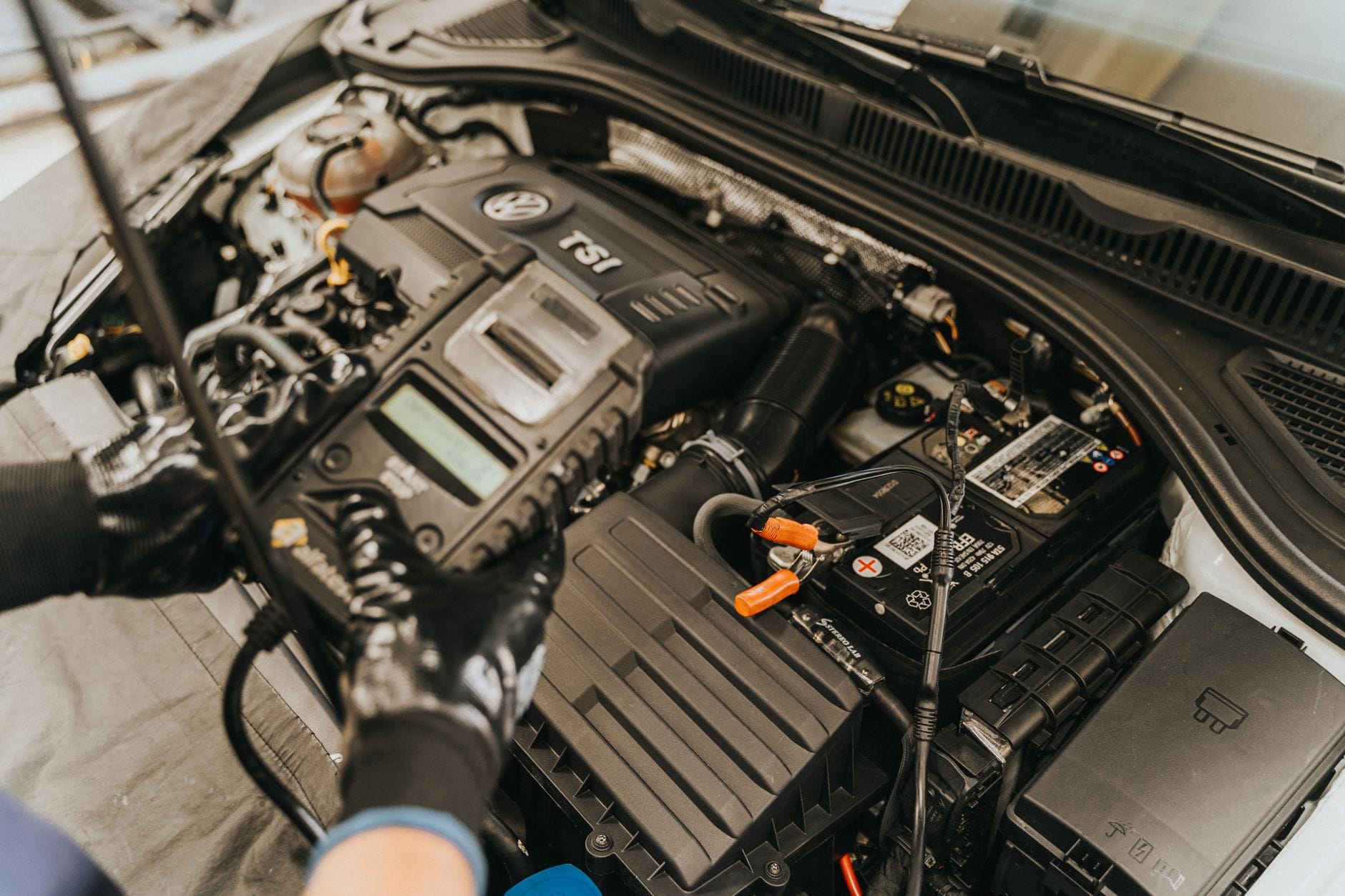 Mechanik diagnozuje silnik Volkswagena miernikiem w komorze silnika