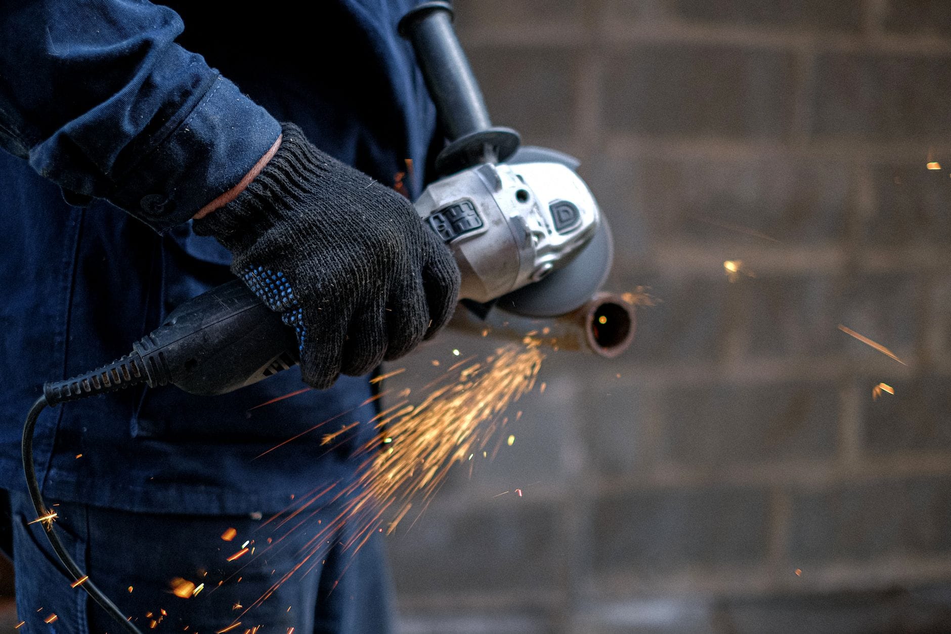 Pracownik tnie metal szlifierką kątową, lecą jasne iskry