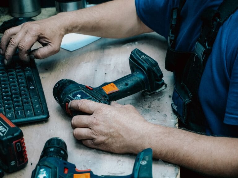 Technik trzyma wiertarko-wkrętarkę i obsługuje klawiaturę przy stanowisku pracy
